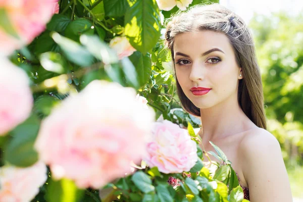 Retrato de cerca de una chica bonita cerca de rosas rosadas —  Fotos de Stock