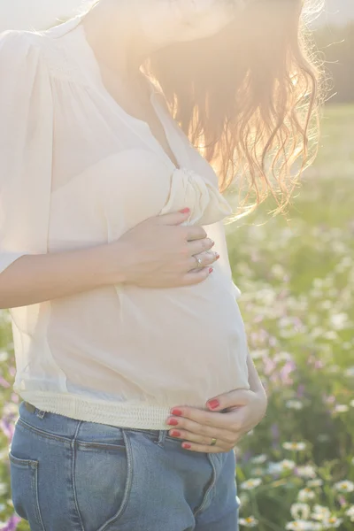 Buik van zwangere vrouw in zonsondergang lichten — Stockfoto