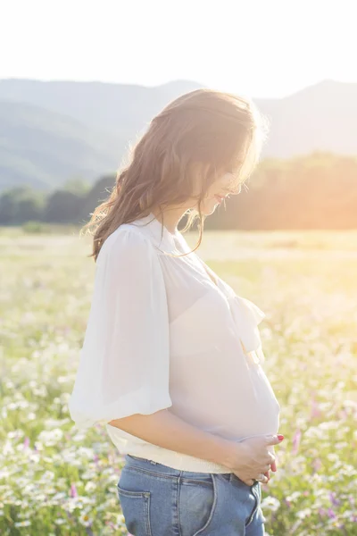 Femme enceinte dans les lumières du coucher du soleil — Photo