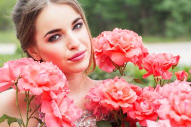 Güzel kadın pembe Gül bush oturuyor 
