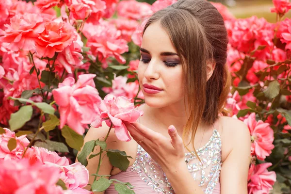 Chica bonita cerca de arbusto de rosas rosadas — Foto de Stock