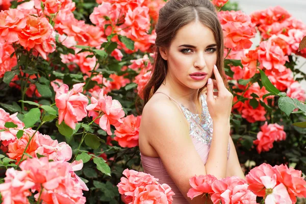 Pretty woman near bush of pink roses outdoors — Stock Photo, Image