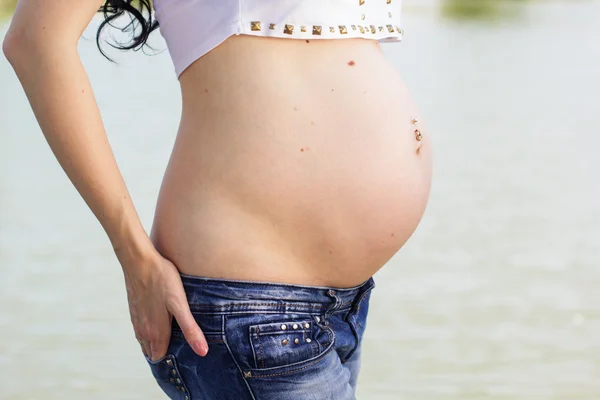 Magen på gravid flicka nära floden — Stockfoto