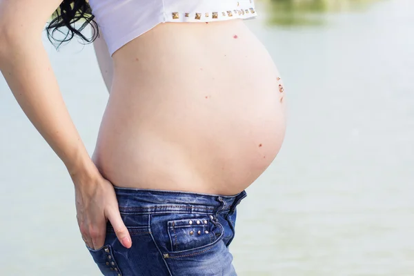 Barriga de menina grávida perto do lago — Fotografia de Stock