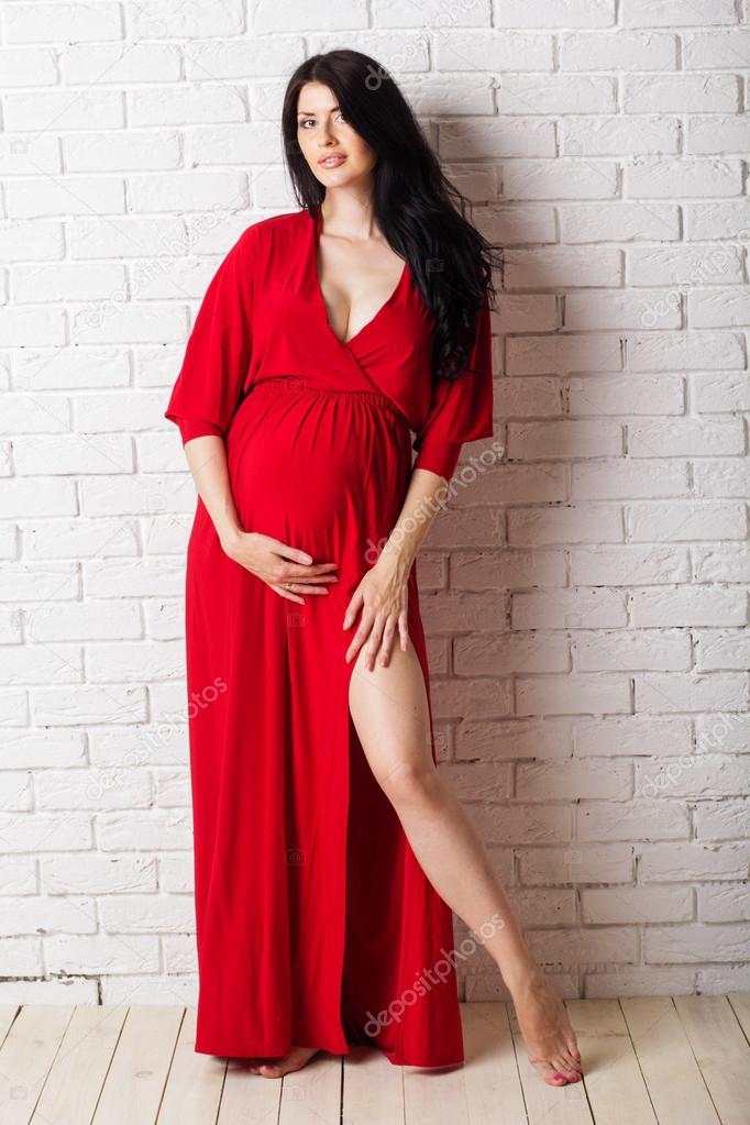 Studio portrait of beautiful pregnant woman in red dress