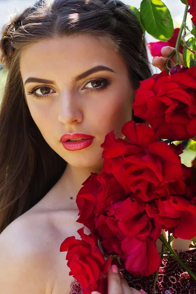 Retrato de mujer hermosa posando cerca de rosas —  Fotos de Stock