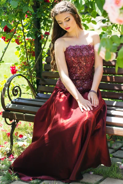 Beautiful woman is sitting on bench in park — Stock Photo, Image