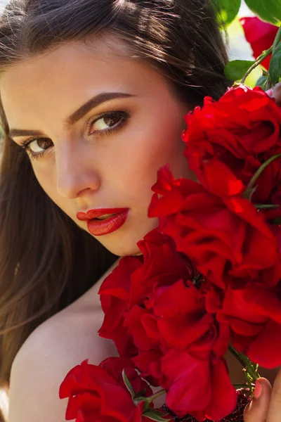 Mode porträtt av vacker kvinna poserar nära rosor — Stockfoto