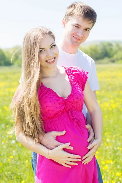 Happy couple girl with husband in flowers field — Stockfoto