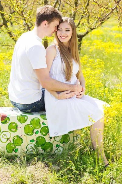 Happy couple girl with boyfriend in flowers garden — Stock Photo, Image