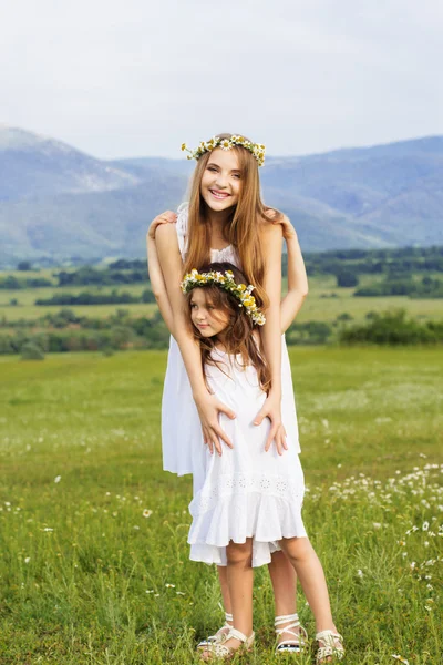 Dos hermanas bonitas en el prado con bonitas vistas a la montaña —  Fotos de Stock