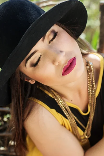 Retrato de mulher bonita em chapéu preto perto de madeiras — Fotografia de Stock