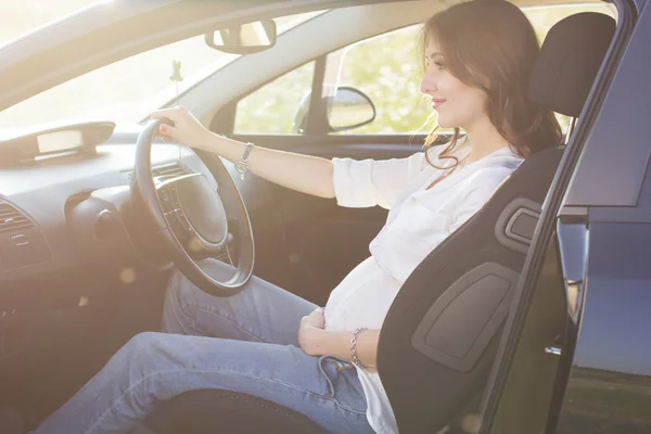 Schwangere hübsche junge Frau sitzt im Auto — Stockfoto