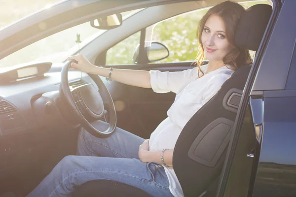 Zwangere mooie jonge vrouw zit in zwarte auto — Stockfoto