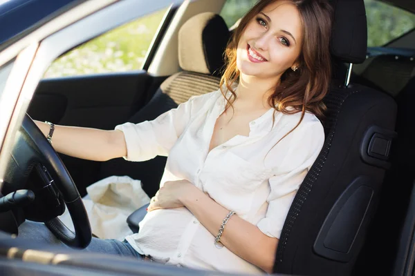 Pregnant happy young woman at the wheel of her car — Stock Photo, Image