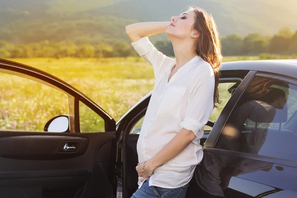 Беременная счастливая молодая женщина возле машины на природе — стоковое фото