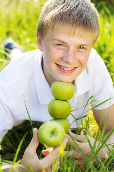 Lindo sonriente adolescente chico con verde manzanas — Foto de Stock