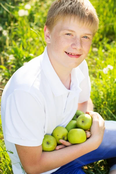 Adolescente guapo chico es holding verde manzanas — Foto de Stock