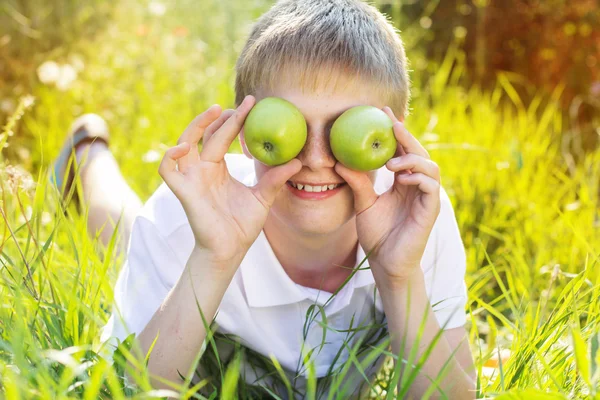 Teen blonde boy is holding green apples — Stock Photo, Image