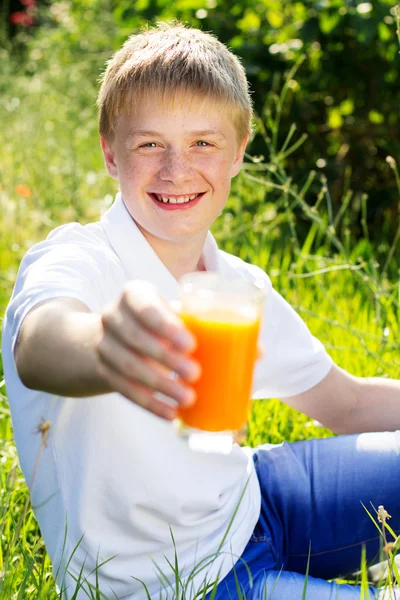 Teen chłopiec trzyma szkła z soku pomarańczowego — Zdjęcie stockowe