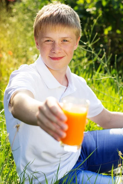 Adolescente chico está sosteniendo vidrio con jugo de naranja — Foto de Stock