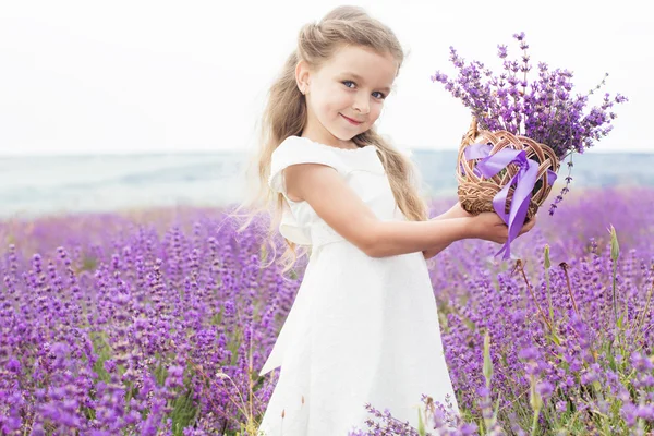 Menina feliz no campo de lavanda com cesta de flores — Fotografia de Stock