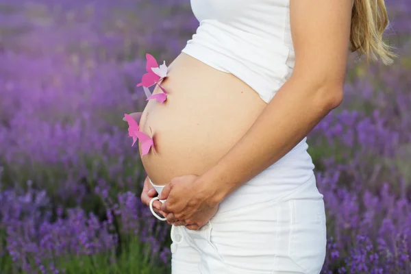 Pretty pregnant woman with paper butterflies on her belly — Stock Photo, Image