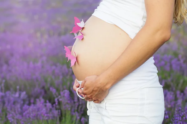 Velmi těhotná žena s papírové motýly v břiše — Stock fotografie