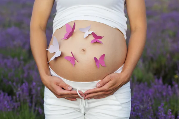 Velmi těhotná žena s papírové motýly v břiše — Stock fotografie