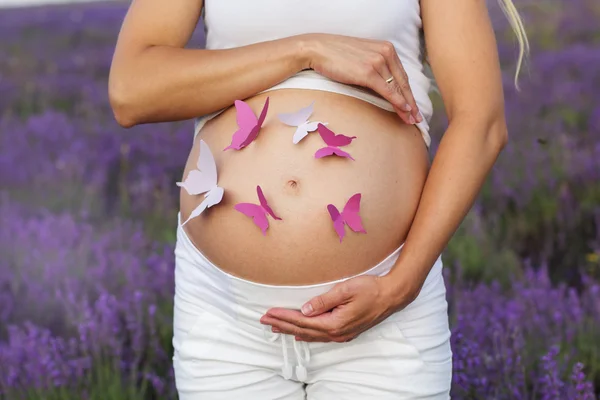 Vrij zwangere vrouw met vlinders op haar buik — Stockfoto