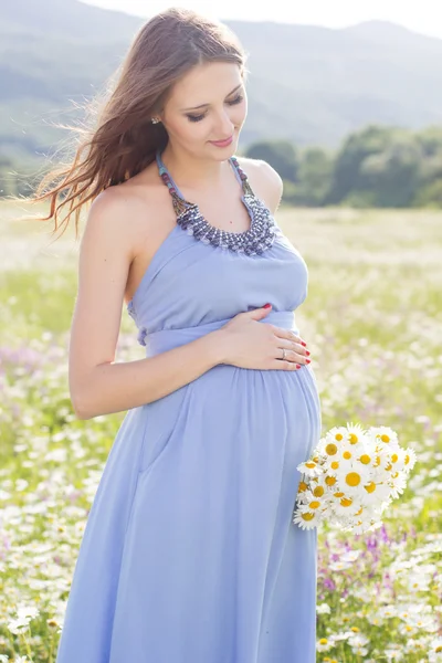 Pregnant woman with bouquet of daisy flowers — Stock Photo, Image