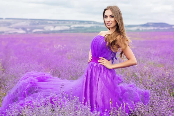 Mooie lachende vrouw draagt mode jurk op lavendel — Stockfoto
