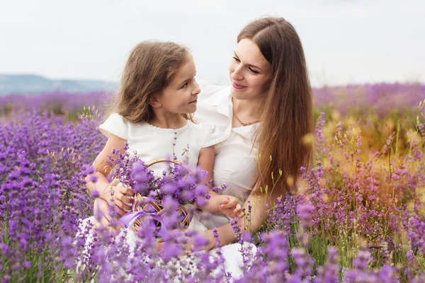 Barn tjej med mamma i lavendel fält håller korg Royaltyfria Stockfoton
