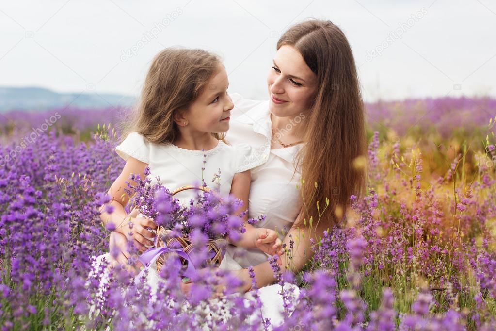 Child girl with mother in lavender field are holding basket