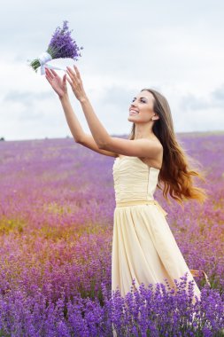 Pretty girl is wearing wedding dress at purple lavender field