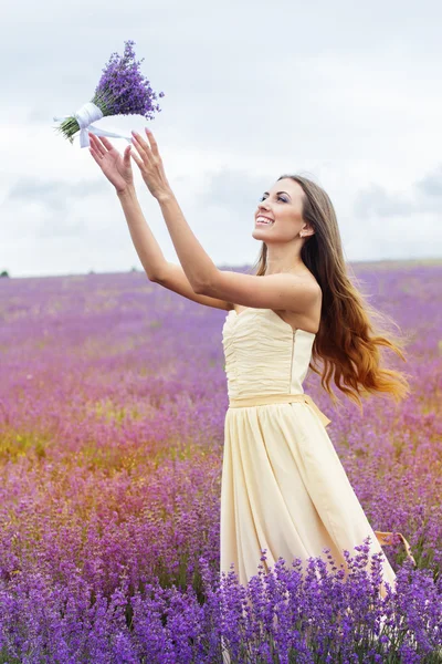 Pretty girl is wearing wedding dress at purple lavender field — Stockfoto