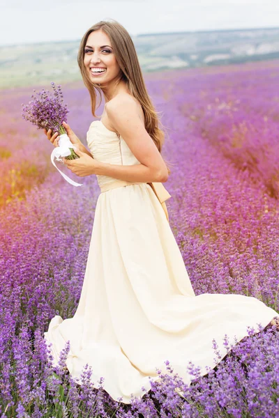 Pretty smiling girl is wearing dress at purple lavender field — Zdjęcie stockowe