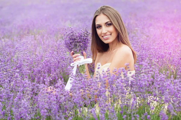 Porträt eines Mädchens mit Blumenstrauß im Lavendelfeld — Stockfoto
