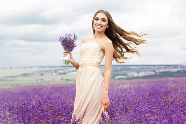 Pretty smiling girl is wearing dress at purple lavender field Stockfoto