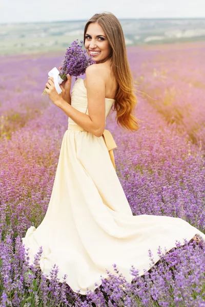 Pretty smiling girl is wearing dress at purple lavender field Royaltyfria Stockbilder
