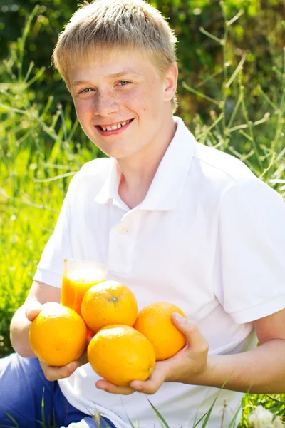 Adolescente chico está sosteniendo vidrio con jugo de naranja — Foto de Stock