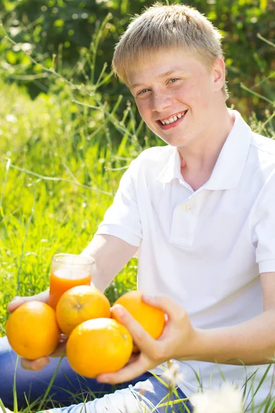 Teenager boy is holding glass with orange juice and fruits — Zdjęcie stockowe