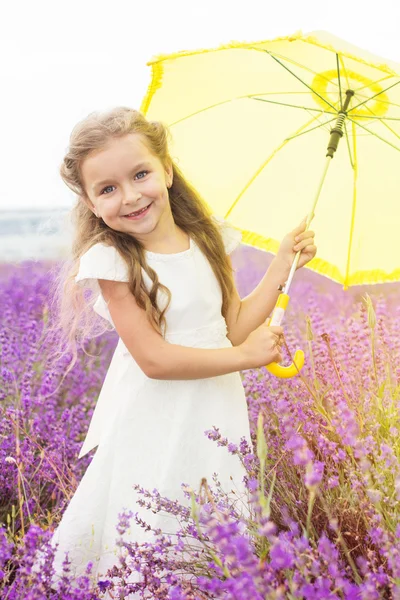 Menina bonito feliz no campo de lavanda com guarda-chuva amarelo — Fotografia de Stock