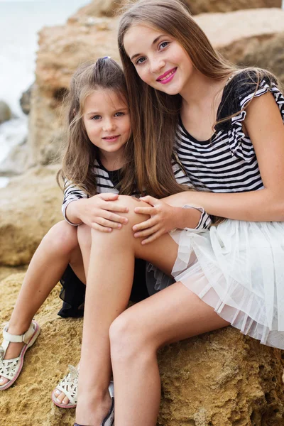 Retrato de duas meninas irmãs sentadas na praia — Fotografia de Stock