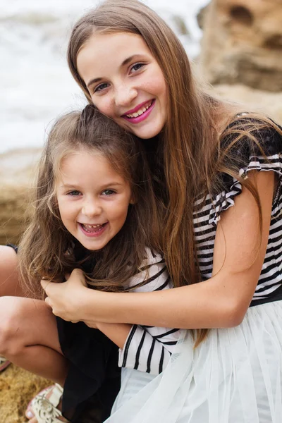 Две милые улыбающиеся девушки сидят на пляже — стоковое фото