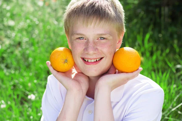 Nastolatek chłopiec trzyma dwie pomarańcze — Zdjęcie stockowe