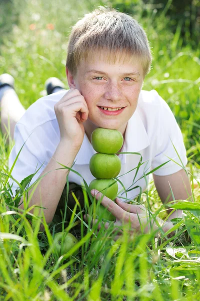 Lindo sonriente rubia adolescente chico con pirámide de verde manzanas — Foto de Stock