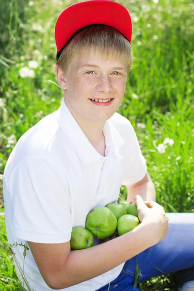 Adolescente chico está usando rojo gorra celebración de manzanas — Foto de Stock