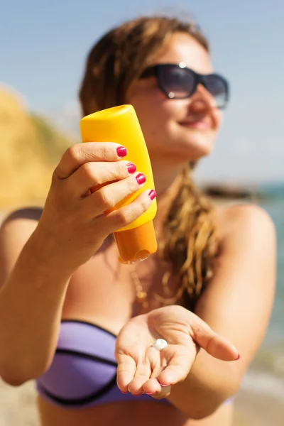 Woman is holding yellow tube with sunscreen tan lotion — Stock Photo, Image