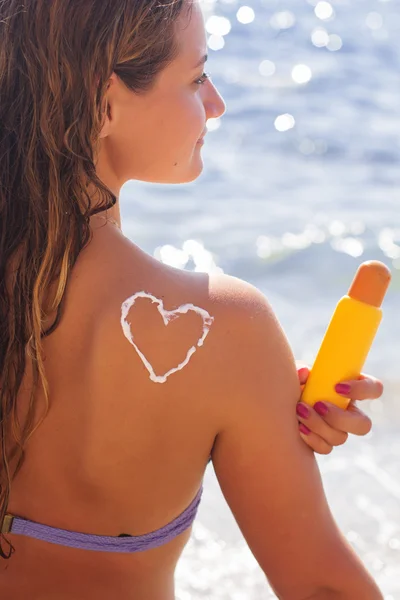 Woman is holding yellow tube with sunscreen tan lotion — Stock Photo, Image